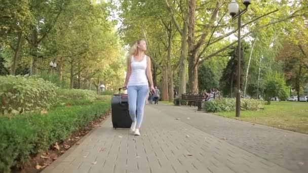 Ragazza con una valigia passeggiando lungo il parco . — Video Stock