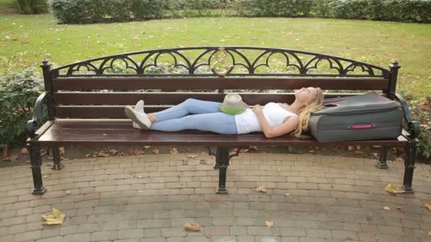 Fille avec une valise reposant sur un banc — Video