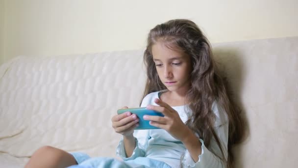 Girl child with a cell phone browses the Internet — Stock Video