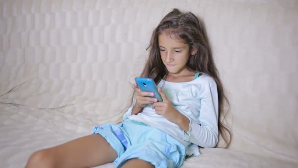 Girl child with a cell phone browses the Internet — Stock Video