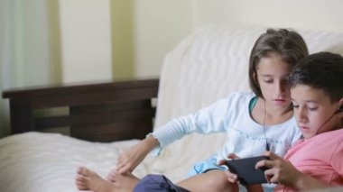 Gençler earphones ile Smartphone kullanarak. kız ve erkek kardeşim ile bir telefon