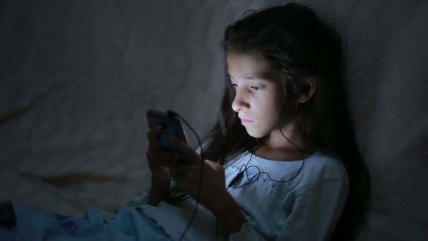 Bambina utilizzando un telefono cellulare di notte — Video Stock