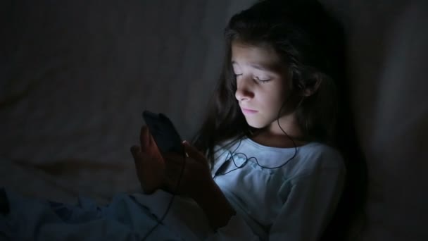 Маленькая девочка по ночам пользуется мобильным телефоном — стоковое видео