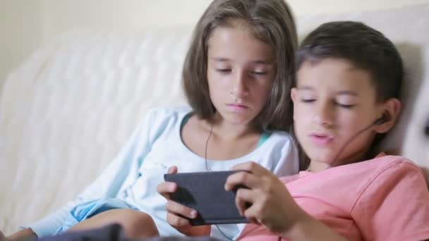 Teenagers using smartphone with earphones. brother and sister with a phone — Stock Video