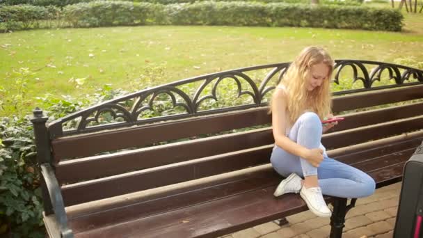 Giovane ragazza con una valigia scrive messaggi al telefono — Video Stock