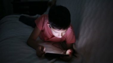 Genç çocuk bir cep telefonu veya bir yatakta smartphone ile oynamak. gece