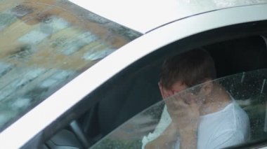 üzgün adam arabanın içinde ağlıyor. sokakta yağmur. Histerik erkekte