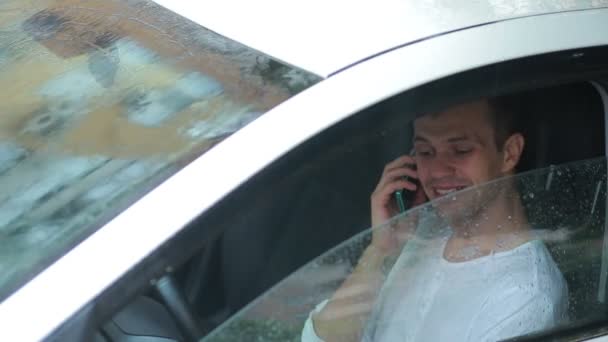 Hombre hablando en un teléfono celular mientras está sentado en el coche. conductor sonriente — Vídeo de stock