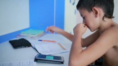 Genç çocuk bir cep telefonu kullanarak ödev yapmak. doğal video