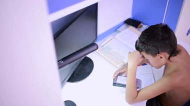 Genç çocuk bir cep telefonu kullanarak ödev yapmak. doğal video