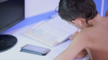 Genç çocuk bir cep telefonu kullanarak ödev yapmak. doğal video