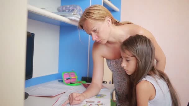 Chica haciendo la tarea junto con su madre. Chica hace lecciones — Vídeos de Stock