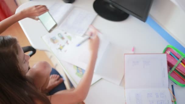 Colegiala haciendo deberes en la mesa hojea a través del libro. Chica hace lecciones — Vídeos de Stock