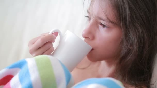 Ziek kind meisje in een bed. ziek kind drinkt thee — Stockvideo