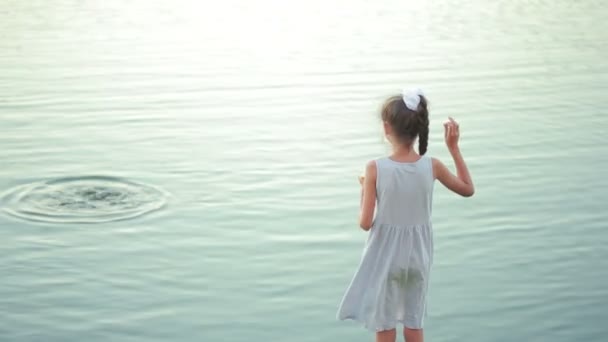 Маленька дівчинка в рожевому одязі годує риб у садовому ставку. дитина біля озера — стокове відео