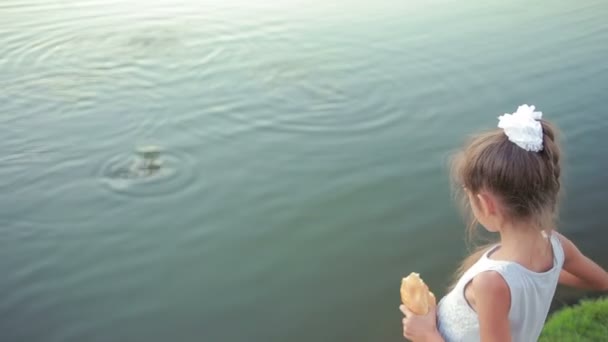 Kis lány a rózsaszín ruhákat, a kerti tóban halak etetése. gyermek a tónál — Stock videók