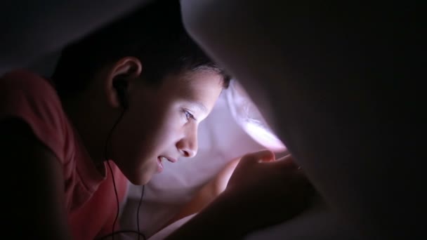 Young boy playing with a cellphone or smartphone on a bed. night — Stock Video