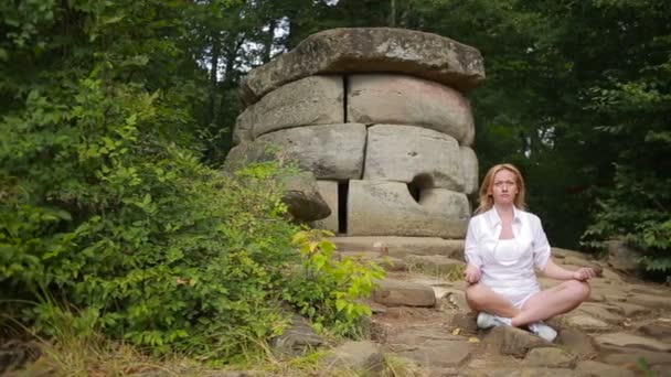 Frau sitzt und meditiert auf steinernen Dolmen — Stockvideo