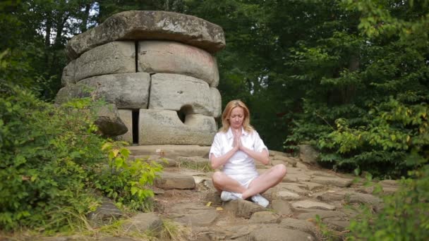 Mulher sentada e meditando em pedra dolmen — Vídeo de Stock