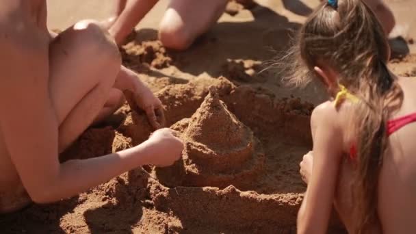 Mãe com filhos na praia. construir um castelo de areia. menino e menina — Vídeo de Stock