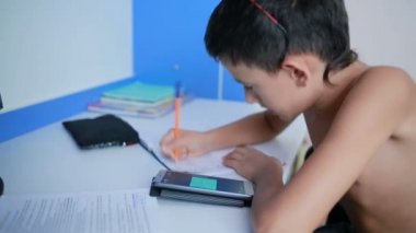 Genç çocuk bir cep telefonu kullanarak ödev yapmak. doğal video