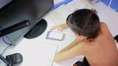 Genç çocuk bir cep telefonu kullanarak ödev yapmak. doğal video
