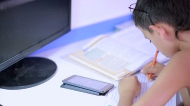 Genç çocuk bir cep telefonu kullanarak ödev yapmak. doğal video