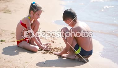 çocuklar. erkek ve kız sahilde kum ile oynuyor. Kumdan kale inşa