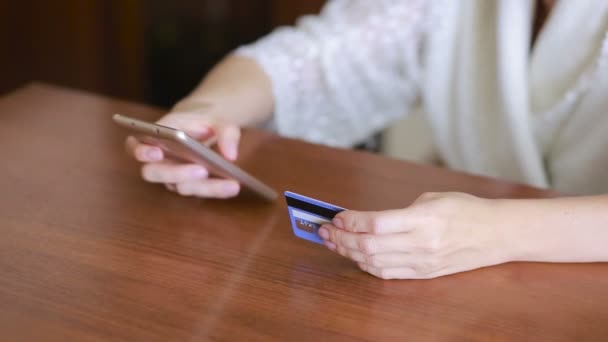 Женщина делает покупку с помощью смартфона и банковской карты . — стоковое видео