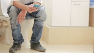 bir hela üstünde oturan adam ve cep telefonunda görünüyor