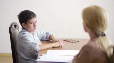 Genç çocuk sessizce oturumu sırasında genç psikolog ile oturuyor..