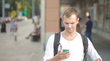 Telefon bir sokak ortasında yazarak adam. Manifatura smartphone cep telefonu ile genç adam.