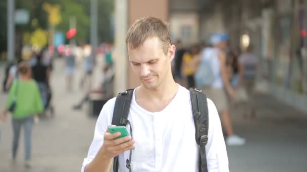 Man te typen op de telefoon in het midden van een straat. Jonge kerel texting op smartphone. — Stockvideo