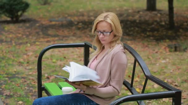 Blonde Woman Reading Book on Brench in Autumn Park. — Stock Video