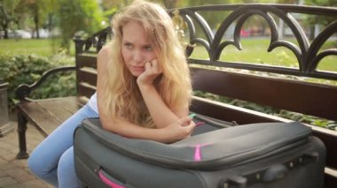 bavulla bankta oturan üzgün kız.