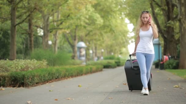 Femme marchant avec des bagages dans les mains, parlant sur smartphone — Video