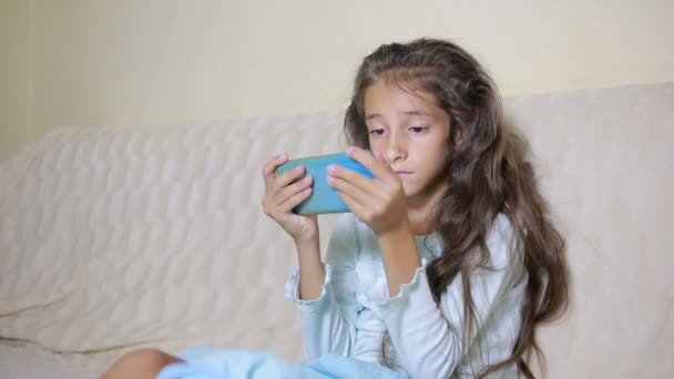 Girl child with a cell phone browses the Internet — Stock Video