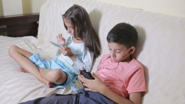 Adolescentes usando smartphone con auriculares. hermano y hermana con un teléfono — Vídeo de stock