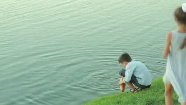 Piccola ragazza in abiti rosa che alimenta i pesci in uno stagno da giardino. bambino vicino al lago — Video Stock
