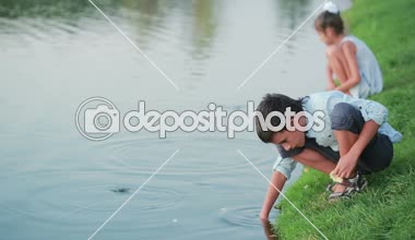 Bahçe gölet balık besleme pembe elbiseleri küçük kız. çocuğun yanında göl