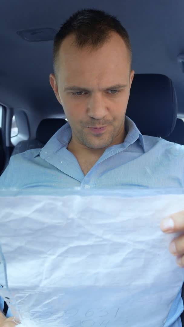 垂直。开车的男性司机在车里检查纸质文件。复制空间 — 图库视频影像