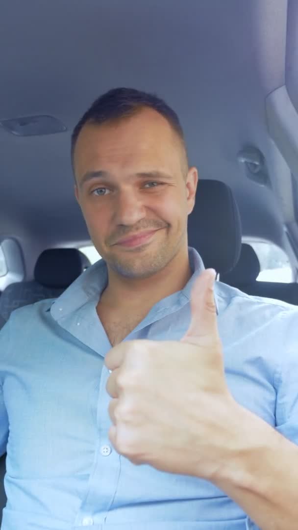 車の中で親指を立てている若いハンサムな男の縦の肖像画 — ストック動画