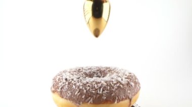 female hand puts jewelry butt plug in chocolate donut. isolated white background