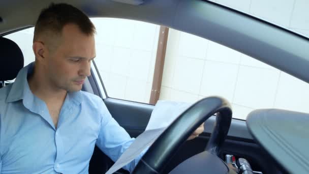 Zdenerwowany kierowca w samochodzie bada dokumenty papierowe. przestrzeń kopiowania — Wideo stockowe