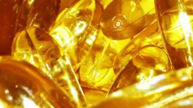 Kavanozun içinde sıvı vitamin bulunan saydam sarı kapsüller.