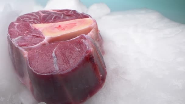 Экстремальный крупный план, подробности. кусок говяжьего мяса на кости на льду с паром — стоковое видео