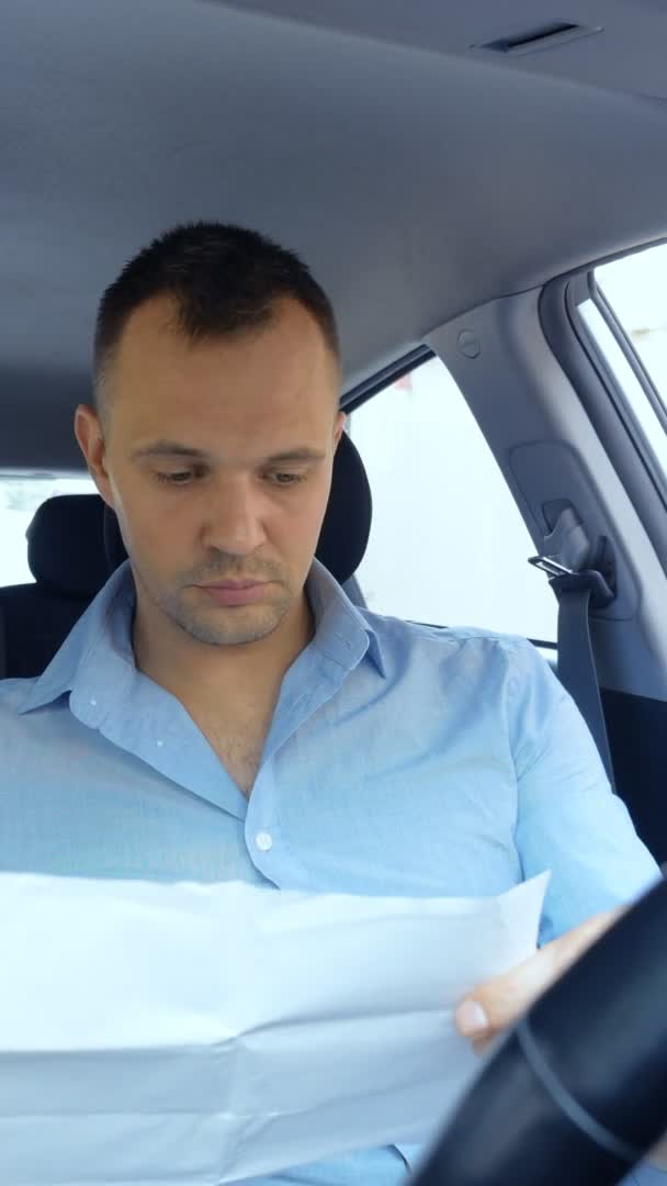 Vertical. conductor masculino molesto en el coche examina los documentos en papel. espacio de copia — Vídeos de Stock