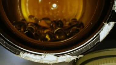 Kavanozun içinde sıvı vitamin bulunan saydam sarı kapsüller.