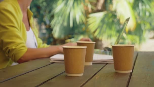 Workaholic woman working on laptop in cafe outdoors with three cups of coffee — Stock Video