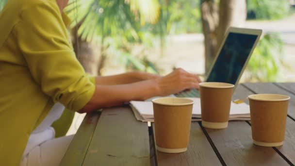 Mujer adicta al trabajo en el ordenador portátil en la cafetería al aire libre con tres tazas de café — Vídeo de stock